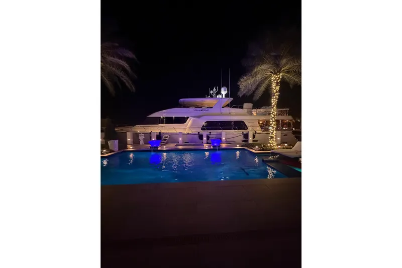  Yacht Photos Pics 2014 Pacific Mariner 85 Motor Yacht docked at night by illuminated pool and palm trees.