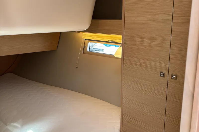 Gem Yacht Photos Pics 2022 Dufour 390 cabin interior with bed, window, and wooden cabinetry.