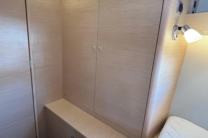 Gem Yacht Photos Pics Interior cabin of 2022 Dufour 390 yacht with wooden cabinetry and wall-mounted light.