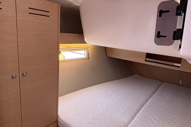 Gem Yacht Photos Pics Modern bedroom interior of 2022 Dufour 390 yacht with double bed and wooden cabinets.