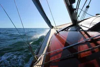 2023 Tofinou 9.7 sailboat navigating through ocean waves under clear blue sky.