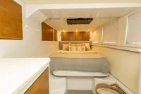 Luxurious cabin interior of 2018 Tag 60 yacht with cozy bed and wooden accents.