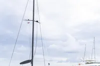 2018 Tag 60 catamaran docked in marina, overcast sky, luxury yachts in background.