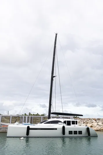  Yacht Photos Pics Sleek 2018 Tag 60 catamaran docked in calm waters under cloudy skies.