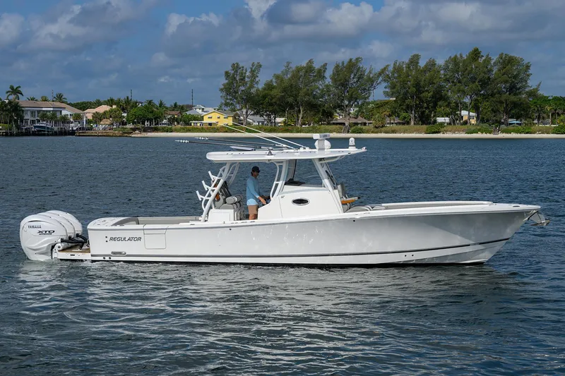  Yacht Photos Pics 2024 Regulator 37 boat cruising on a calm lake under a partly cloudy sky.