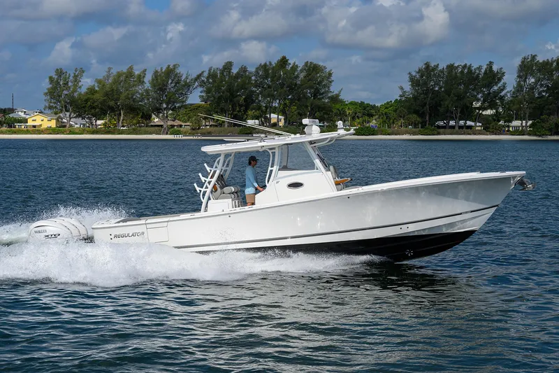  Yacht Photos Pics 2024 Regulator 37 boat cruising on a calm lake under a partly cloudy sky.