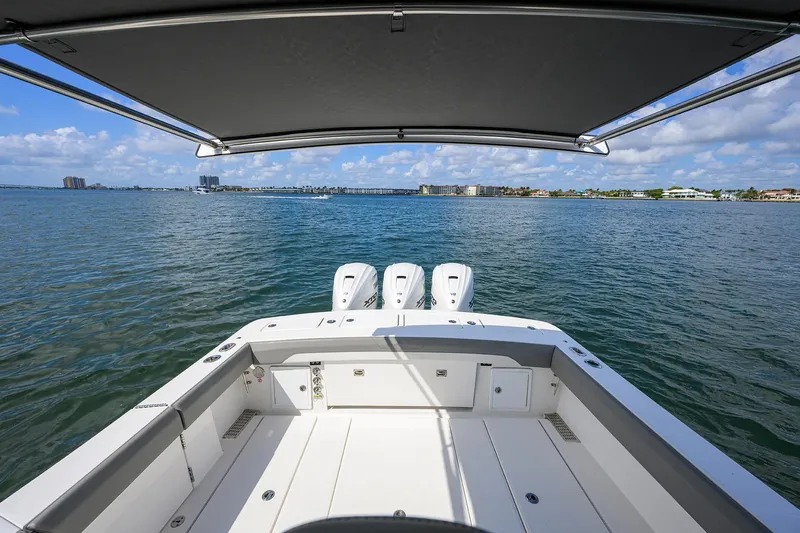  Yacht Photos Pics 2024 Regulator 37 boat with triple engines, shaded deck, and scenic water view.