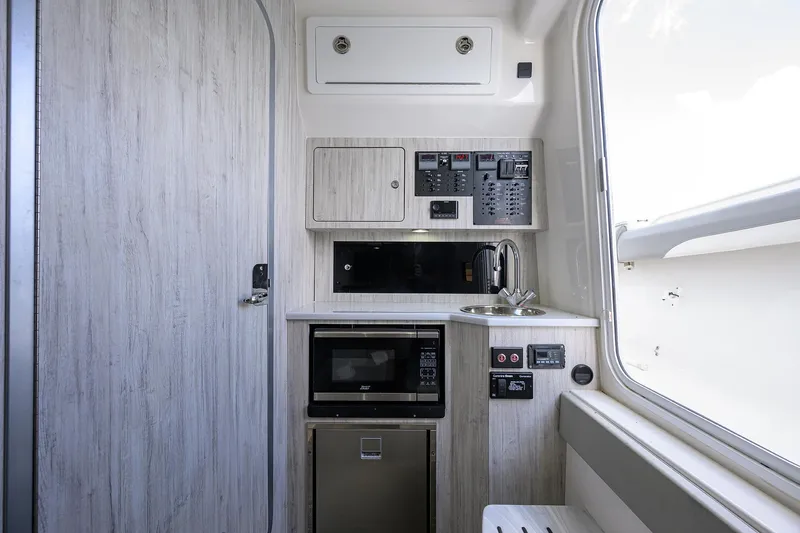  Yacht Photos Pics 2024 Regulator 37 interior with kitchenette, featuring microwave, sink, and control panel.