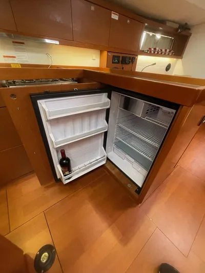 Joie De Vivre Yacht Photos Pics Open fridge in 2014 Beneteau Oceanis 48 yacht kitchen with wooden cabinetry.