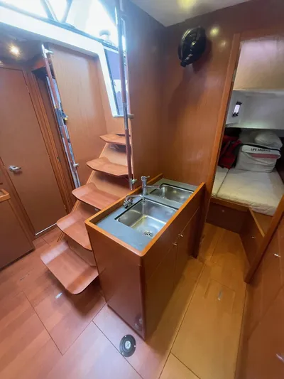 Joie De Vivre Yacht Photos Pics Interior of 2014 Beneteau Oceanis 48 yacht with wooden stairs and compact kitchen area.