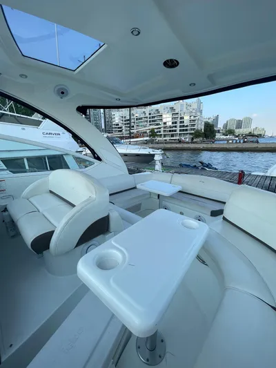  Yacht Photos Pics 2009 Cruisers Yachts 360 Express interior with seating and table, docked by waterfront buildings.