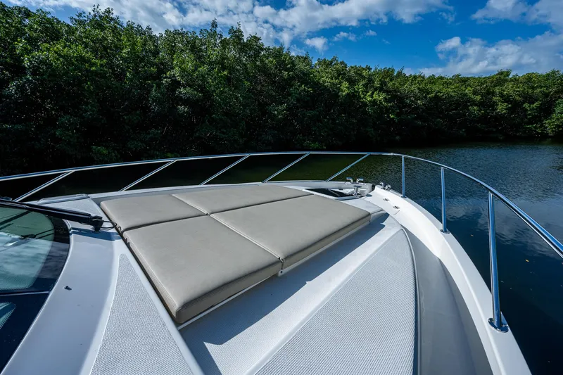 Ciento Siete Yacht Photos Pics 2020 Maritimo X50 yacht bow with sunpad, surrounded by lush greenery and calm waters.