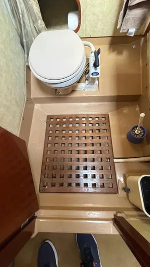 Indigo Yacht Photos Pics Bathroom interior of a 1996 Amel Super Maramu-53 yacht with toilet and wooden floor grate.