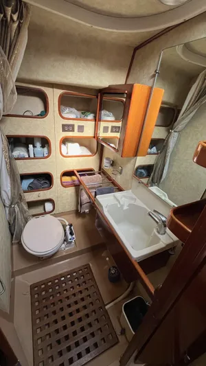 Indigo Yacht Photos Pics Bathroom interior of 1996 Amel Super Maramu-53 yacht with sink, toilet, and storage shelves.