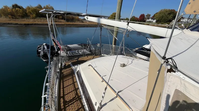 Indigo Yacht Photos Pics 1996 Amel Super Maramu-53 sailboat docked on calm water, surrounded by autumn trees.