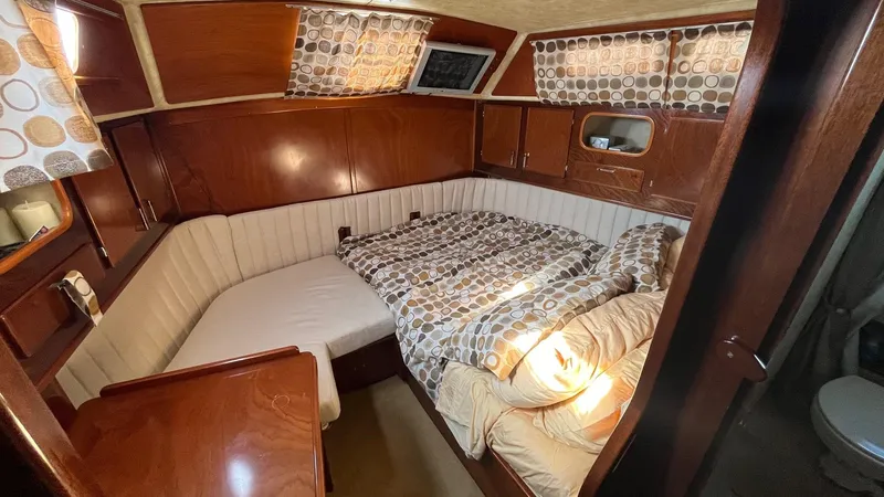 Indigo Yacht Photos Pics Cozy cabin interior of 1996 Amel Super Maramu-53 sailboat with wood paneling and patterned bedding.