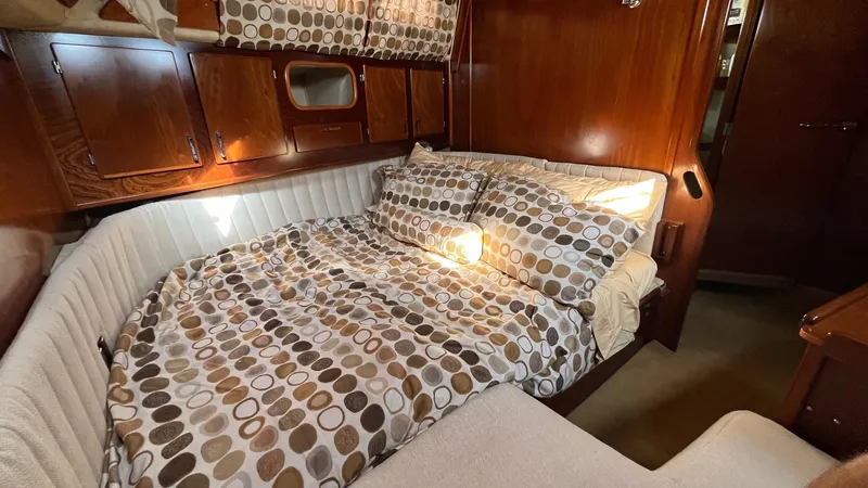Indigo Yacht Photos Pics Cozy cabin interior of 1996 Amel Super Maramu-53 with patterned bedding and wooden accents.
