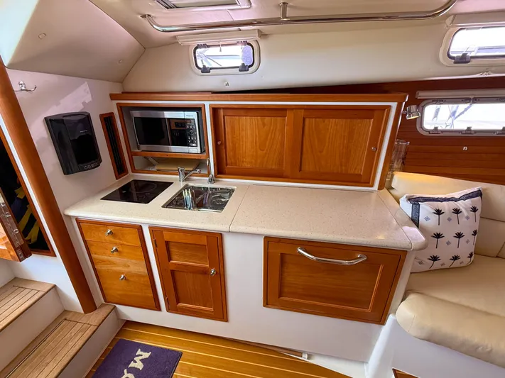 Moncri Yacht Photos Pics Interior of 2012 MJM 36z Downeast yacht with kitchenette, featuring wood cabinetry and modern appliances.