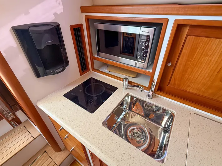 Moncri Yacht Photos Pics Compact kitchen in 2012 MJM 36z Downeast boat with microwave, sink, and stovetop.