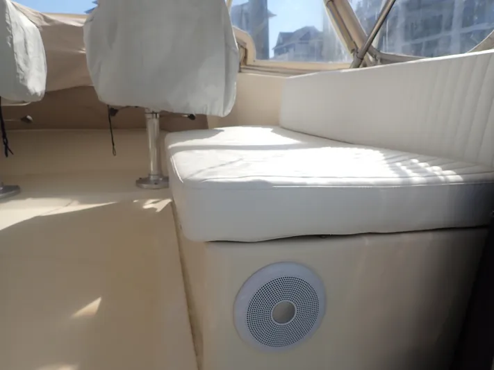 No Quarter Yacht Photos Pics Interior seating of 2006 Mainship 34 Trawler with speaker, white upholstery, and window view.