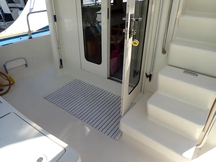 No Quarter Yacht Photos Pics 2006 Mainship 34 Trawler deck with open door and steps, featuring a striped mat.