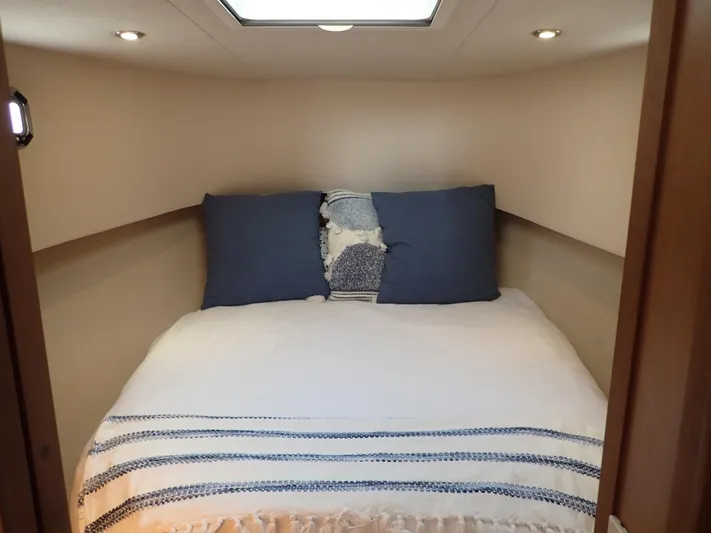 No Quarter Yacht Photos Pics Cozy bedroom in 2006 Mainship 34 Trawler with blue pillows and striped bedding.