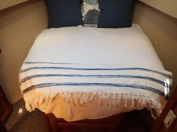 No Quarter Yacht Photos Pics Cozy bed in 2006 Mainship 34 Trawler cabin with striped blanket and pillows.