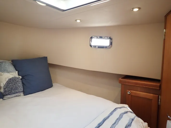 No Quarter Yacht Photos Pics Cozy cabin interior of 2006 Mainship 34 Trawler with bed and porthole window.