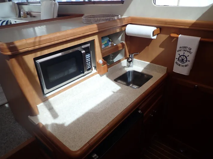 No Quarter Yacht Photos Pics 2006 Mainship 34 Trawler galley with microwave, sink, and wooden cabinetry.