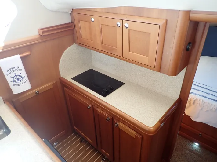 No Quarter Yacht Photos Pics 2006 Mainship 34 Trawler kitchen with wooden cabinets and electric cooktop.