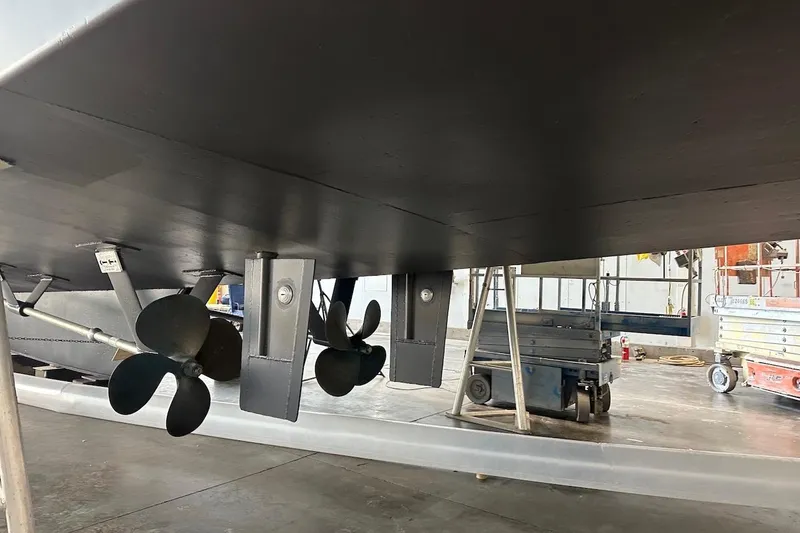 Andiamo Yacht Photos Pics Underside view of 1991 Broward 102 yacht with visible propellers in a workshop.