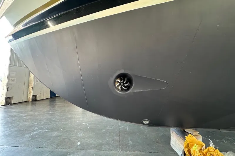 Andiamo Yacht Photos Pics Close-up of a 1991 Broward 102 yacht hull with visible thruster in a shipyard.