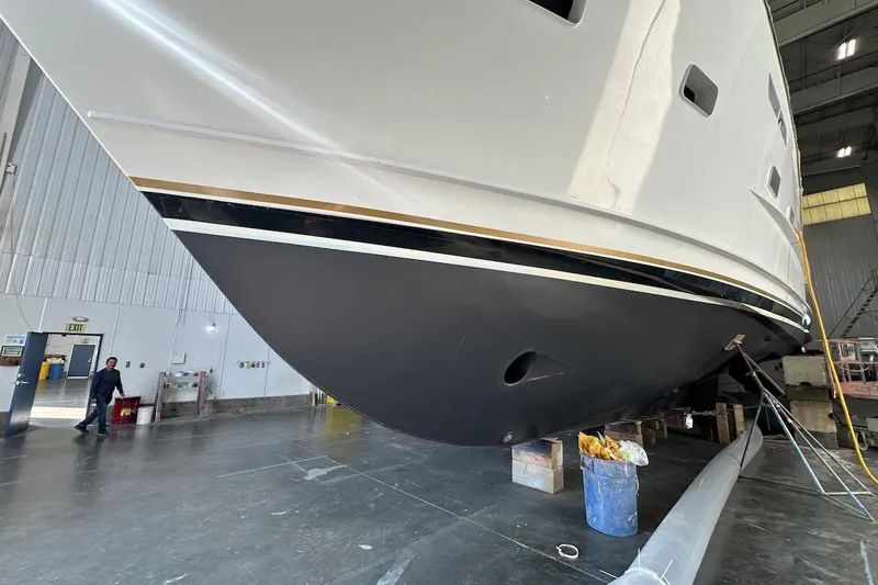 Andiamo Yacht Photos Pics Broward 102 yacht from 1991 in a maintenance facility, showcasing its sleek hull design.