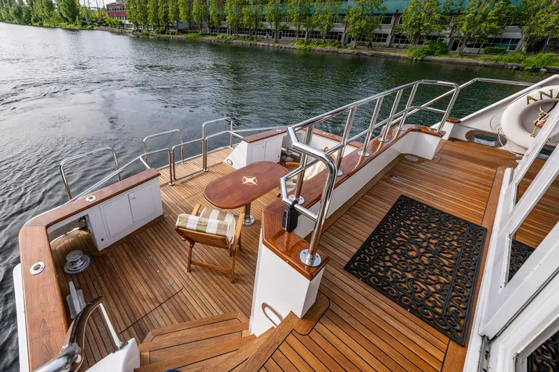 Andiamo Yacht Photos Pics Luxurious Broward 102 yacht deck with wooden flooring, elegant seating, and scenic waterfront view.