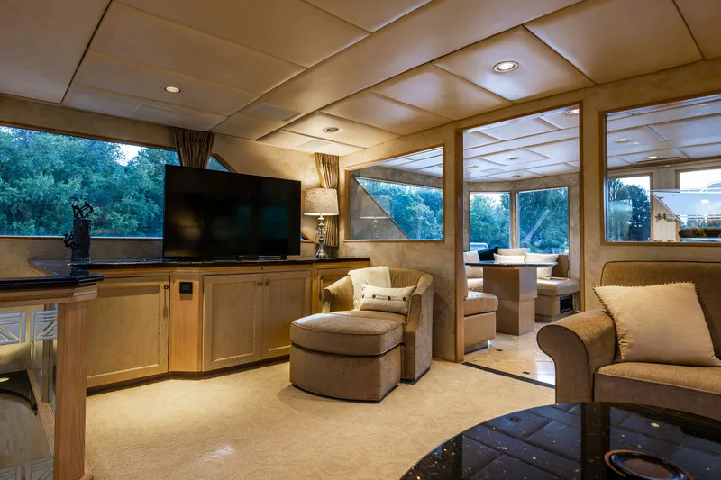 Andiamo Yacht Photos Pics Luxurious interior of a 1991 Broward 102 yacht with elegant seating and large windows.