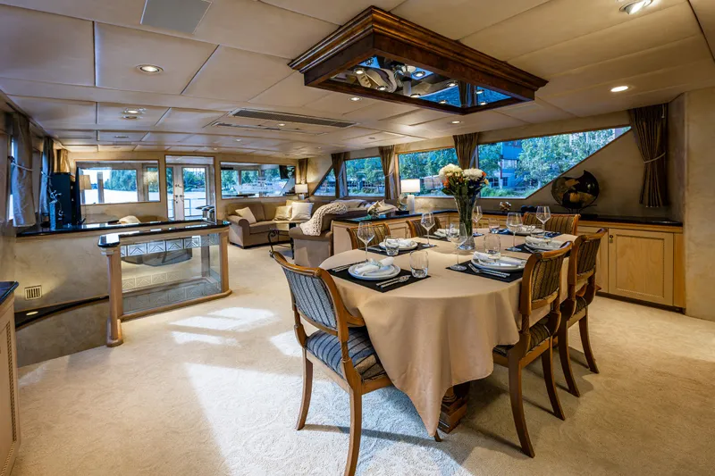 Andiamo Yacht Photos Pics Luxurious interior of 1991 Broward 102 yacht with elegant dining area and plush seating.