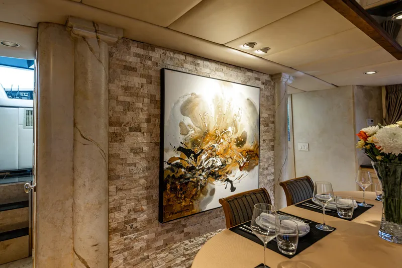 Andiamo Yacht Photos Pics Luxurious dining area on 1991 Broward 102 yacht with elegant artwork and table setting.