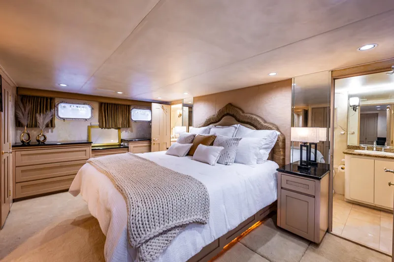 Andiamo Yacht Photos Pics Luxurious bedroom interior on 1991 Broward 102 yacht with elegant decor and cozy bedding.