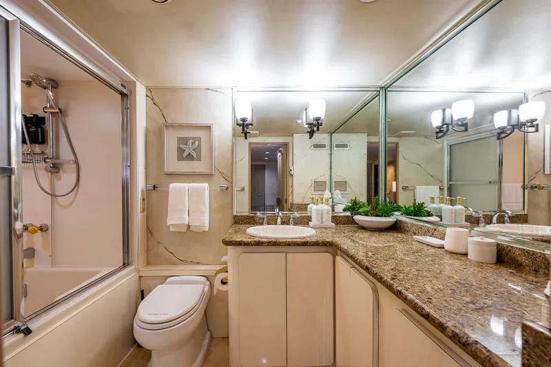 Andiamo Yacht Photos Pics Luxurious bathroom with granite countertops, large mirrors, and elegant lighting on a 1991 Broward 102 yacht.