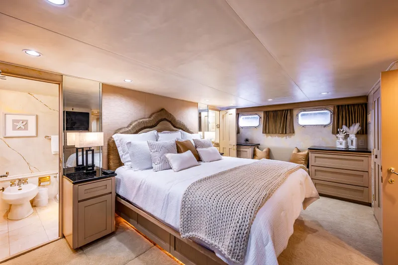 Andiamo Yacht Photos Pics Luxurious bedroom interior on 1991 Broward 102 yacht with elegant decor and cozy bedding.