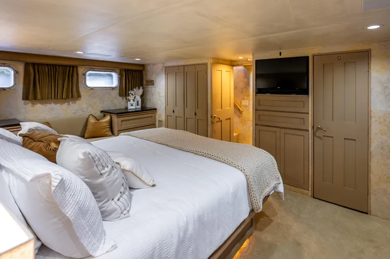 Andiamo Yacht Photos Pics Luxurious bedroom interior on 1991 Broward 102 yacht with elegant decor and modern amenities.