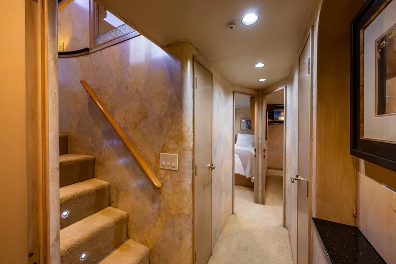 Andiamo Yacht Photos Pics Luxurious hallway in 1991 Broward 102 yacht with carpeted stairs and elegant lighting.