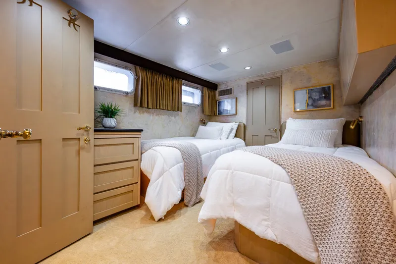 Andiamo Yacht Photos Pics Luxurious twin bedroom on 1991 Broward 102 yacht, featuring elegant decor and cozy bedding.