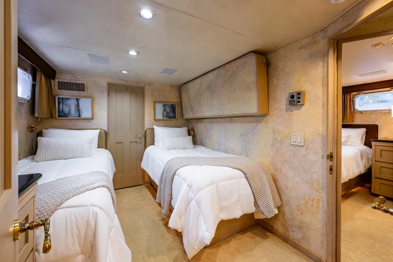 Andiamo Yacht Photos Pics Luxurious twin bedroom in 1991 Broward 102 yacht, featuring elegant decor and cozy bedding.