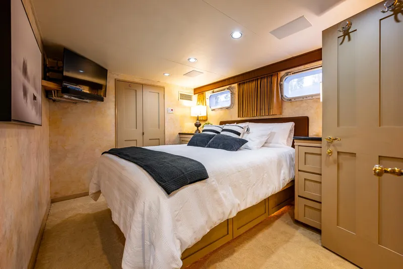 Andiamo Yacht Photos Pics Luxurious bedroom interior on 1991 Broward 102 yacht, featuring cozy bed and elegant decor.
