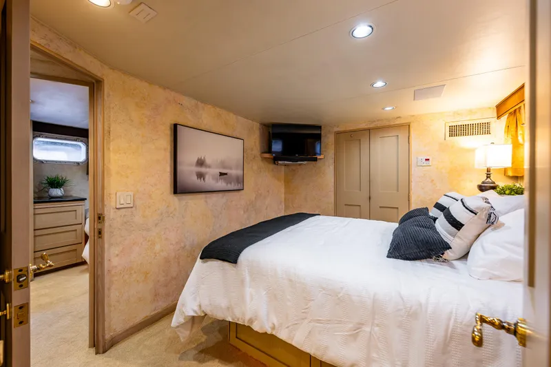 Andiamo Yacht Photos Pics Luxurious bedroom interior on 1991 Broward 102 yacht, featuring cozy bed and elegant decor.