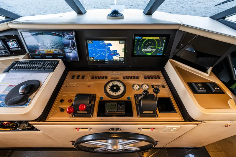 Andiamo Yacht Photos Pics Control panel of a 1991 Broward 102 yacht with navigation screens and steering wheel.