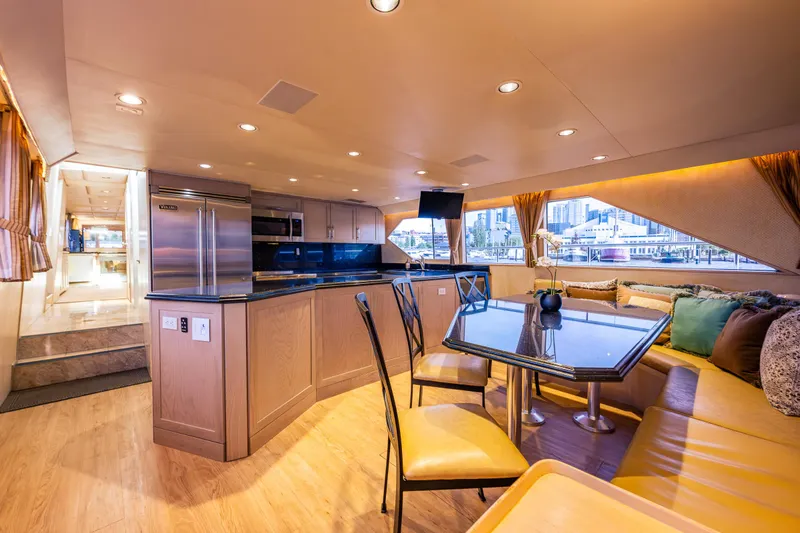 Andiamo Yacht Photos Pics Luxurious interior of 1991 Broward 102 yacht with modern kitchen and dining area.