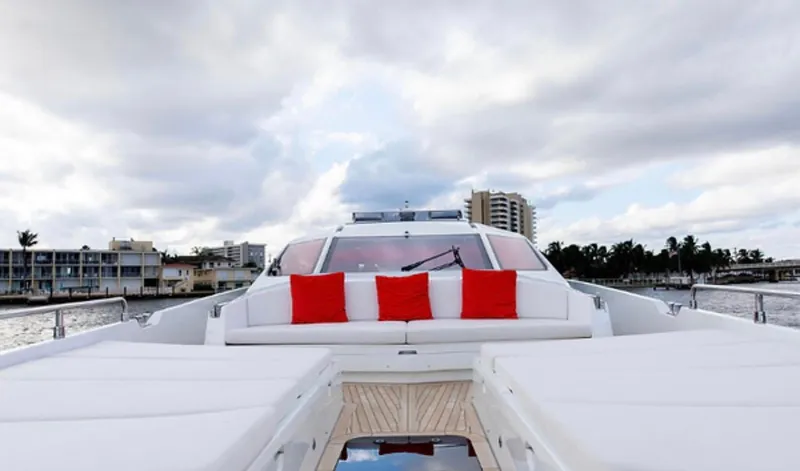  Yacht Photos Pics Luxurious 2019 Numarine 78 yacht with red cushions, cruising near coastal buildings under a cloudy sky.