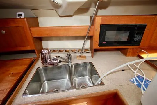  Yacht Photos Pics 2001 Hunter Passage 420 yacht kitchen with double sink, microwave, and wooden cabinetry.